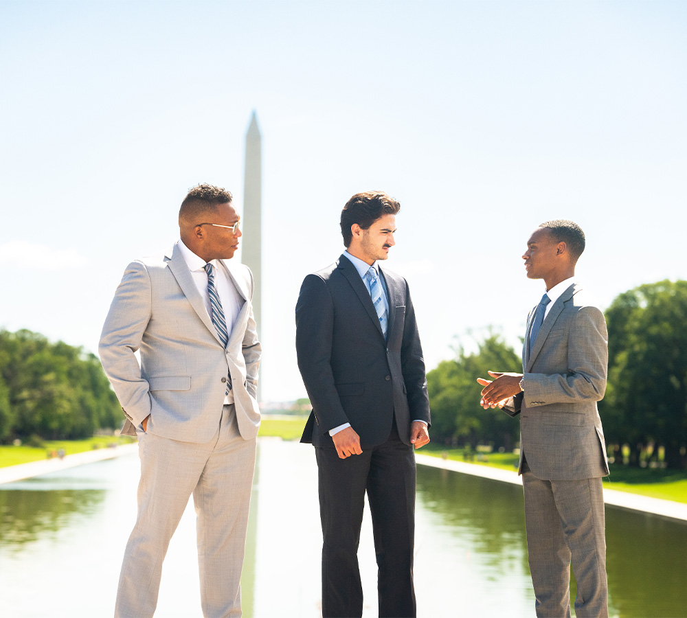 Three pickering fellowship students standing in front of the Washington monument talking